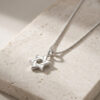 Close-up of a tiny interlocking Star of David pendant in sterling silver on stone