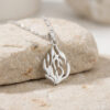 Sterling silver Hebrew flame pendant reading האש שלי (My Fire) leaning on a stone