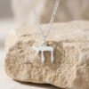 Small sterling silver Chai necklace on a Figaro chain resting on natural stone, Hebrew life symbol pendant