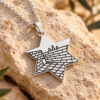 Sterling silver Star of David necklace with Western Wall Kotel engraving, resting on Jerusalem stone with olive leaves