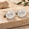 Personalized sterling silver cufflinks with a raised Hebrew name over a Western Wall stone pattern, displayed on Jerusalem stone with olive leaves