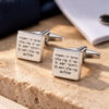 Engraved cufflinks in sterling silver with Hebrew verse lettering, square pair displayed on Jerusalem stone