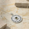 Priestly Blessing Nano Bible necklace lying on a textured stone slab, sterling silver disc and chain