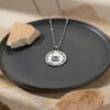 Sterling silver Nano Bible Eshet Chayil Necklace lying on a dark ceramic dish, Hebrew Woman of Valor pendant