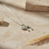 Sterling silver zirconia Chai necklace on travertine stone with dried wheat