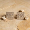 Close view of sterling silver Kotel cufflinks with a raised Hebrew name, surrounded by small Jerusalem stones