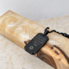 Black Hebrew engraved dog tag necklace resting on olive wood and stone, a Jewish keepsake pendant for men