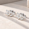 Sterling silver cufflinks with the same Hebrew name cut out on both cufflinks, lying on a light stone surface