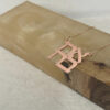 Rose gold plated stacked Ahava Hebrew love necklace leaning on an onyx stone block