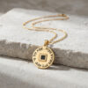 24K gold plated Nano Bible Eshet Chayil Necklace with gold chain lying on a stone slab, Hebrew Woman of Valor pendant