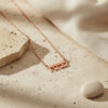 Rose gold plated tiny Hebrew name necklace on a travertine stone, delicate personalized Hebrew pendant
