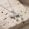 Sterling silver Chai pendant paved with cubic zirconia on a figaro chain, resting on travertine stone