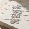 Four sterling silver Hebrew name necklaces laid on a stone block, personalized Hebrew name pendants on fine chains