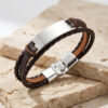 Brown braided leather bracelet with a silver stainless steel nameplate and clasp resting on stone