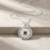 Sterling silver Nano Bible necklace laid on a stone ledge, the chain curving around the round Priestly Blessing pendant