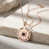 Rose gold plated Nano Bible Eshet Chayil Necklace with rose gold chain draped over a stone block, Hebrew Woman of Valor pendant