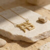 24K gold plated stacked Ahava Hebrew love necklace resting on travertine stone