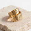24K gold plated Woman of Valor Hebrew engraved wrap ring resting on travertine stone