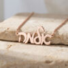 Rose gold plated custom Hebrew script name necklace on travertine stone