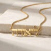 Gold plated tiny Hebrew name necklace spelling a Hebrew name, draped over a travertine stone