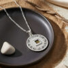 Nano Bible Priestly Blessing pendant on a black ceramic plate, the silver disc contrasting with the dark glaze