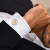 Man in a black suit wearing personalized Hebrew name Kotel cufflinks with a gold name on a white French cuff shirt