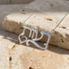 Close-up of a sterling silver Hebrew name pendant with heart and swirl underline on Jerusalem stone