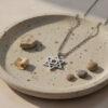 Silver Star of David Nano Bible necklace on a stone dish with pebbles
