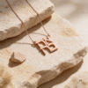 Rose gold plated stacked Ahava Hebrew love necklace close-up on travertine stone