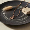 Rose gold plated petite Magen David necklace on a dark ceramic plate