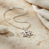 Silver Star of David Nano Bible necklace on a beige stone surface