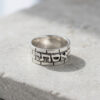 Wide sterling silver Kotel band ring with the Hebrew name Esti, on a gray stone surface
