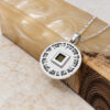 Sterling silver Nano Bible Priestly Blessing pendant resting against a marble block and olive wood
