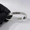 sterling silver Jerusalem Wall cuff bracelet with Hebrew engraving held in a gloved hand