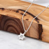 Petite sterling silver Magen David necklace resting on olive wood and white marble