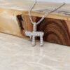Sterling silver Hebrew Chai pendant with cubic zirconia stones on a figaro chain, on a polished wood and marble block