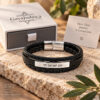 Black leather bracelet engraved Am Yisrael Chai in front of a Gaya Judaica gift box, ready for gifting