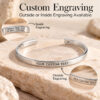 Silver cuff bracelet on stone showing where custom text can be engraved, on the outside or the inside of the cuff