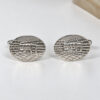 Pair of engraved Jerusalem cufflinks in 925 sterling silver on white fabric, side angle