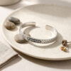 sterling silver Jerusalem Wall cuff bracelet with Hebrew engraving on a ceramic plate with pebbles
