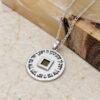 Sterling silver Nano Bible necklace on light stone beside an olive wood block, showing the Hebrew blessing border