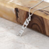Sterling silver Custom Hebrew Name Necklace with a vertical Hebrew name pendant reading Ahava (אהבה), Hebrew for love leaning on a wood and stone block