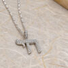 Close view of a sterling silver Chai pendant paved with cubic zirconia, on a marble textured surface