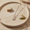 Minimalist silver Star of David necklace on a stone tray with an olive leaf