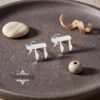 Sterling Silver Chai stud earrings presented on a dark ceramic dish with driftwood detail, modern Judaica styling