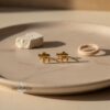 24K Gold Plated Hebrew Chai stud earrings on a wooden plate with twine and stone, lifestyle Judaica gift