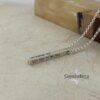 Custom engraved silver Hebrew bar necklace resting on natural stone