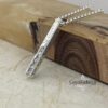 Engraved silver Hebrew bar pendant necklace displayed on olive wood