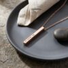 Rose gold engraved Hebrew bar necklace presented on a dark plate