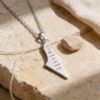 Sterling silver Israel map necklace engraved in Hebrew script, resting on a stone